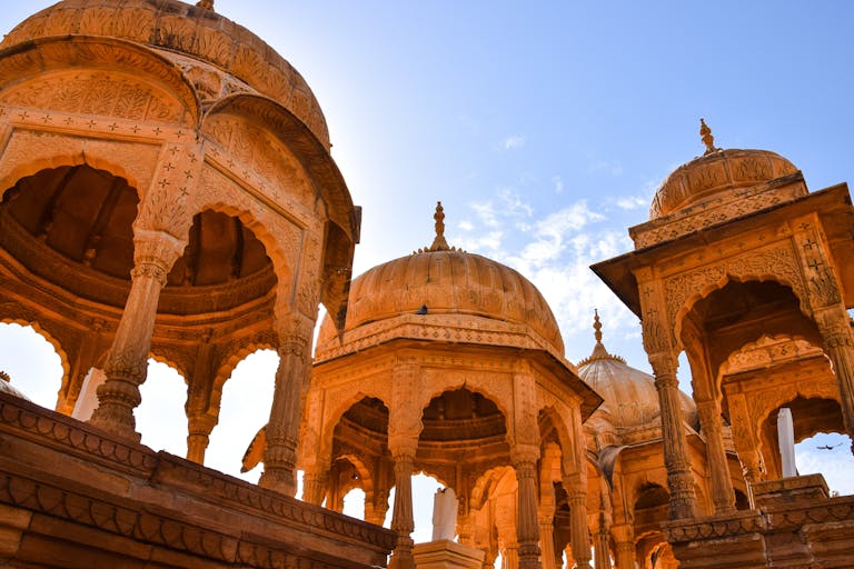 Beautiful domed structures showcasing traditional Indian sandstone architecture under sunlight.